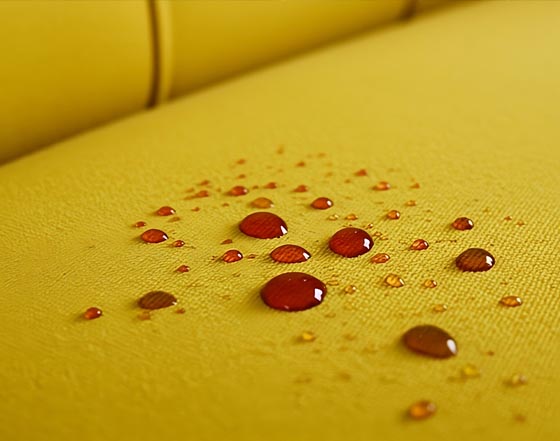 srovnání impregnovaného a neimpregnovaného čalounění sedačky - víno na ošetřeném povrchu tvoří kuličky
