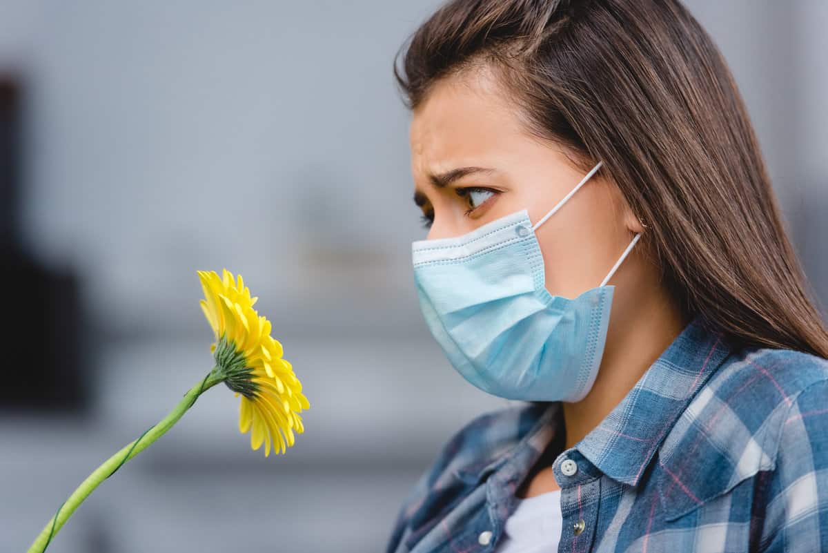 girl-in-face-mask-sniffing-flower