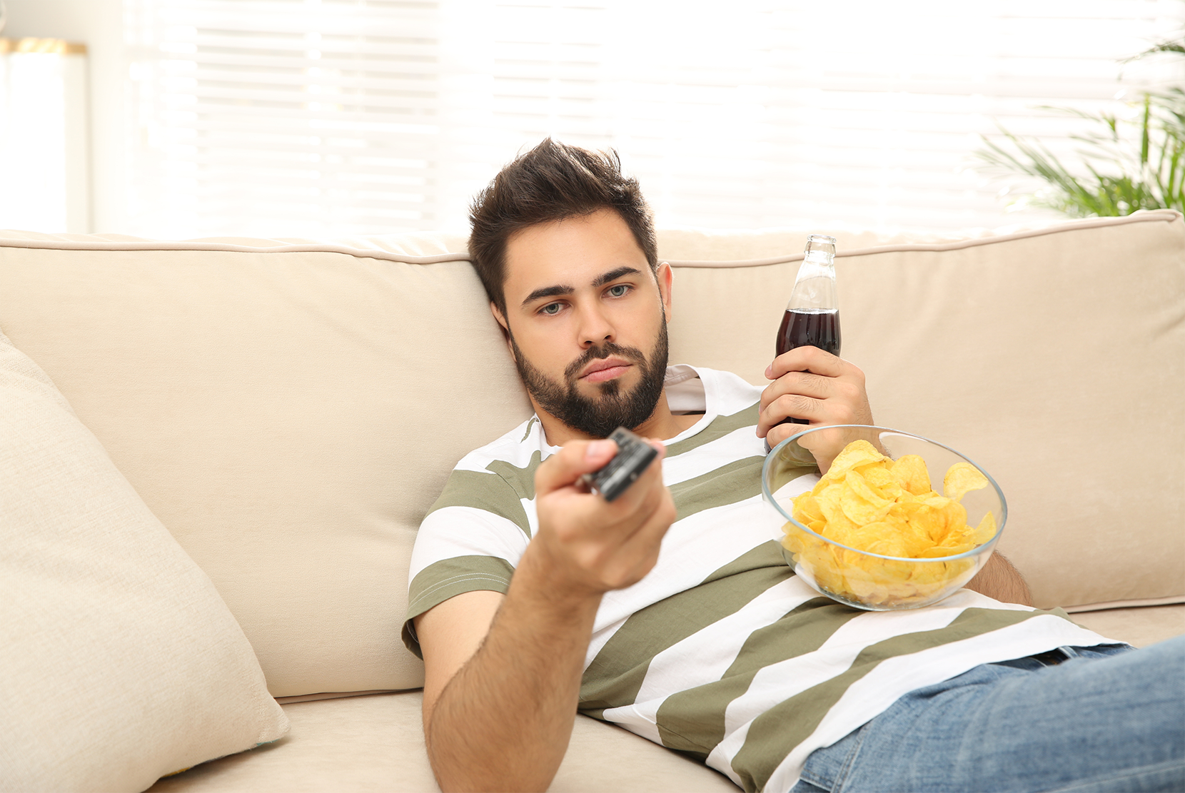 man-laying-on-the-couch-eating-chips