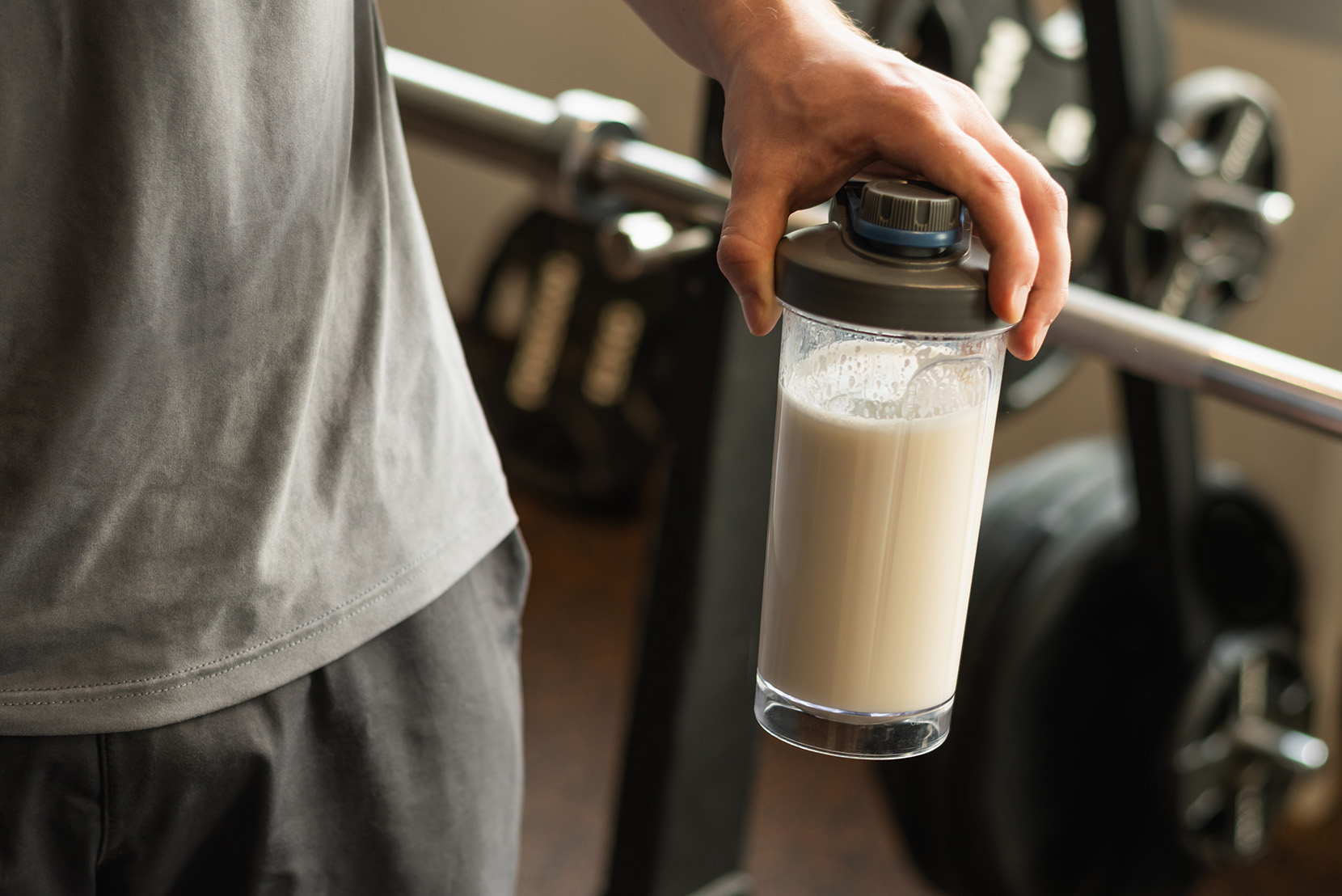 muž-vo-fitku-drží-shaker-s-proteínom