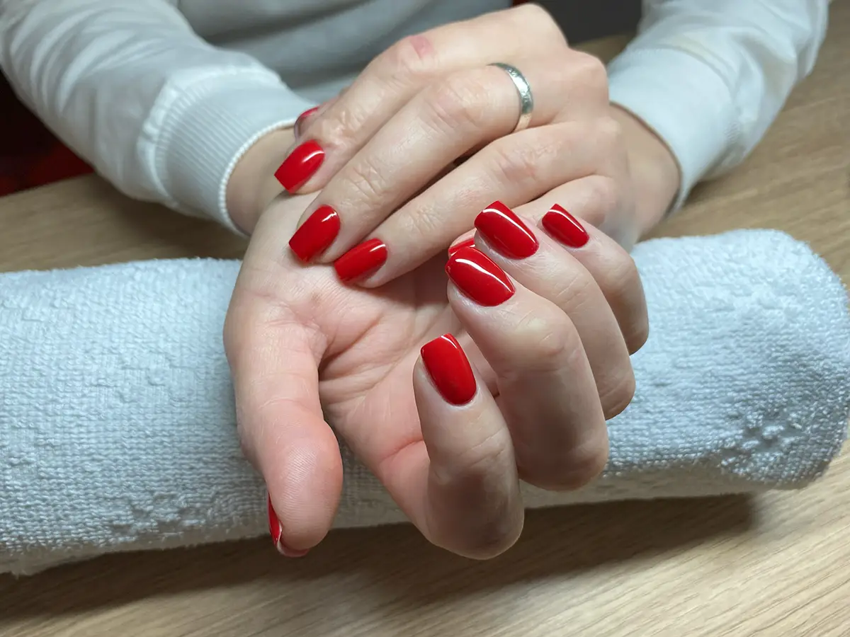 Ruce modelky s krásnou manikúrou a červenými nehty na ručníku v Nehtovém Studiu NG Pedikura Praha.