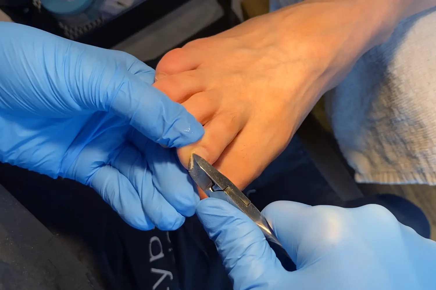 Pedikérka stříhá nehty nohou klientky pomocí nůžek v Nehtovém Studiu NG Pedikura Praha.