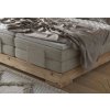 Boxspring posteľ - detail rohu - sivé čalúnenie a masívne drevo