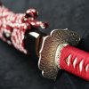 Řemeslná replika katany se skládanou čepelí, červeným opletem rukojeťi a černou lesklou pochvou se třpytem. o