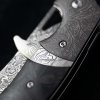Zavírací damaškový nůž Dellinger Auslöser Carbon s černou rukojetí z uhlíkových vláken a bohatě gravírovaným ocelovým bolsterem. h