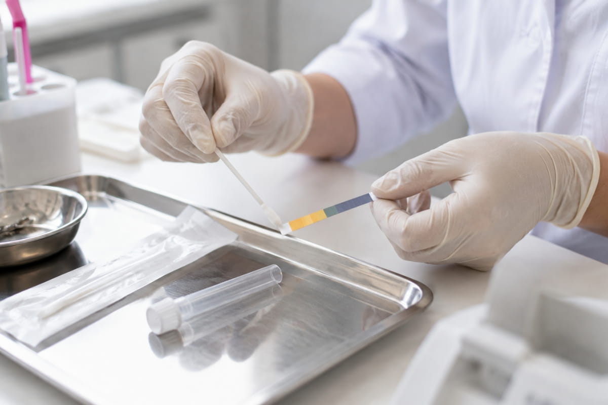 Zdravotník hodnotí vzorek pomocí pH testovacího proužku