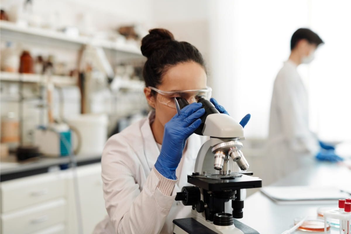 Laboratorní pracovník zkoumá klinický vzorek pomocí mikroskopu