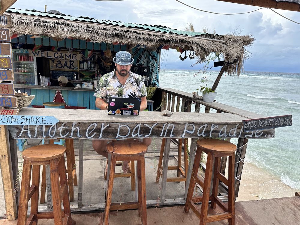 Zbyněk Fridrich s notebookem u plážového baru na Bali s výhledem na moře