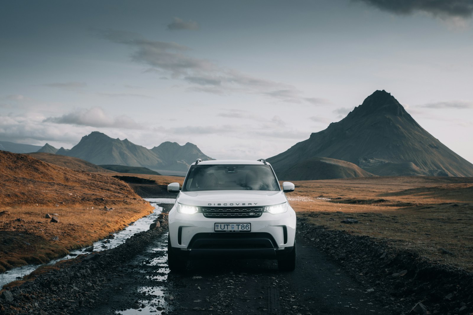 Bílé SUV Land Rover na silnici mezi horami
