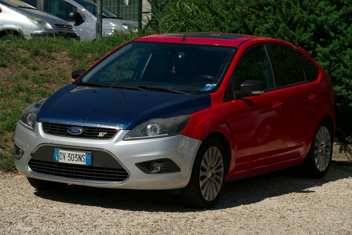 Ford Focus s červenými dveřmi zaparkovaný na parkovišti
