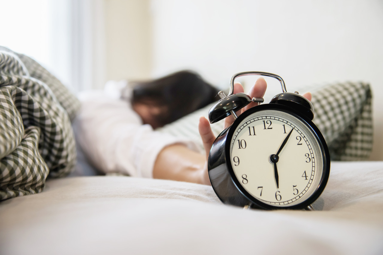 sleepy-woman-reaching-holding-alarm-clock