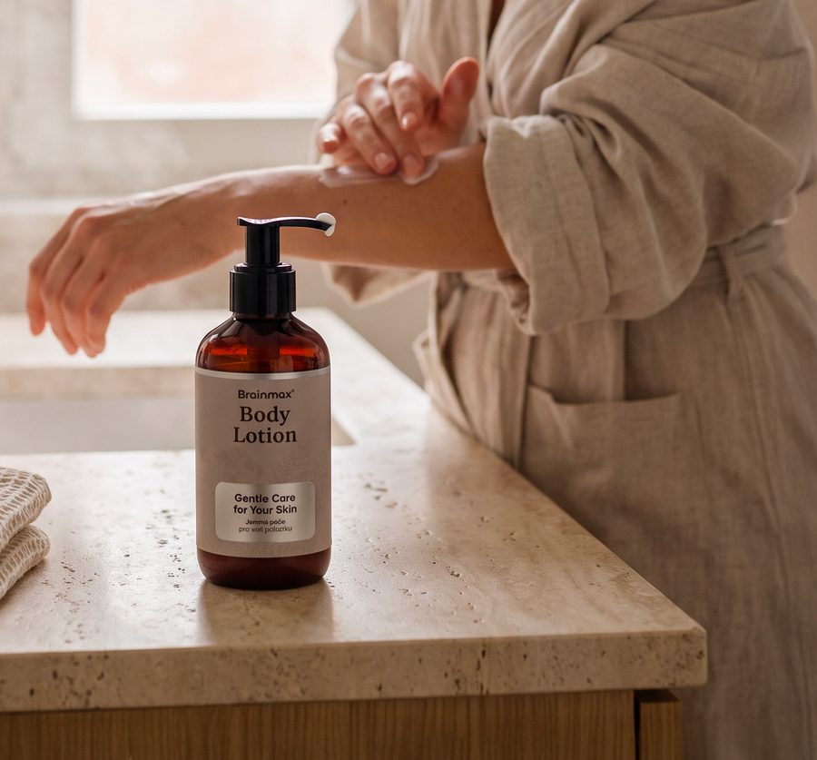 Žena v županu aplikuje Brainmax Body Lotion na paži