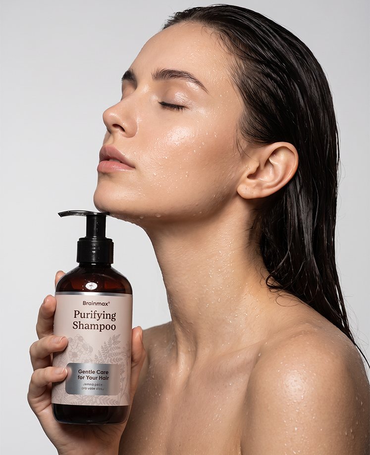 Žena s mokrými vlasy drží lahev Brainmax Purifying Shampoo