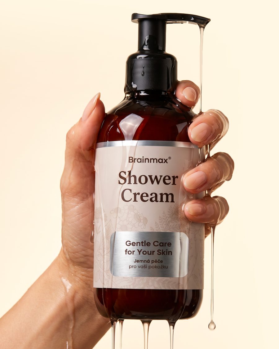 Ruka držící láhev Brainmax Shower Cream se stékajícím sprchovým krémem