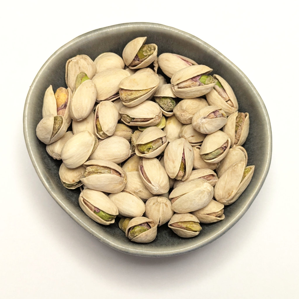 Dvě misky s pistáciemi – jedna s vyloupanými jádry, druhá s pistáciemi ve skořápce.