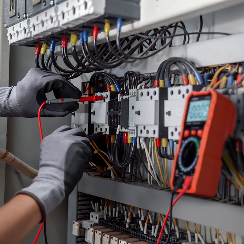 Multimetr Solight V33 přichycený magnetem na rozvaděči, technik měří sondami na svorkách stykače