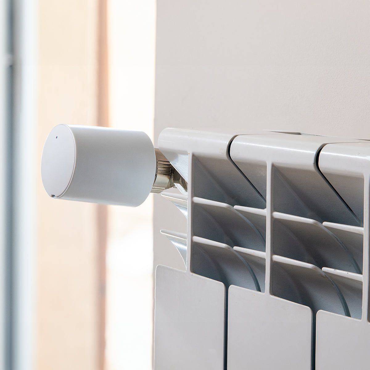 Termostatická hlavice namontovaná na ventilu radiátoru u okna