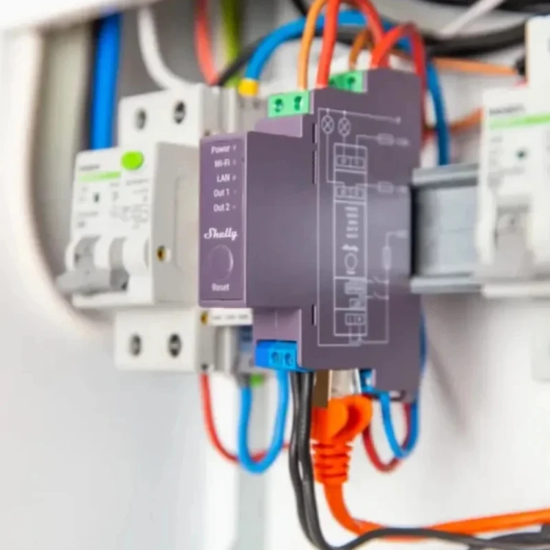 Šedý modul Shelly Pro 2 v rozvaděči na DIN liště mezi jističi, se zapojenými vodiči a ethernetovým kabelem