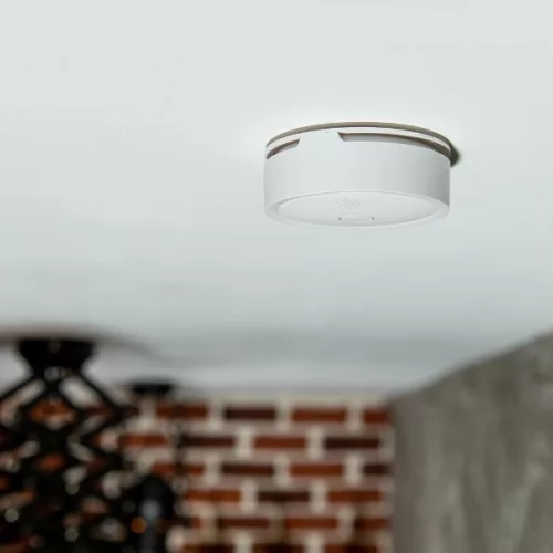 Bílý detektor kouře Shelly Plus Smoke Alarm namontovaný na stropě místnosti