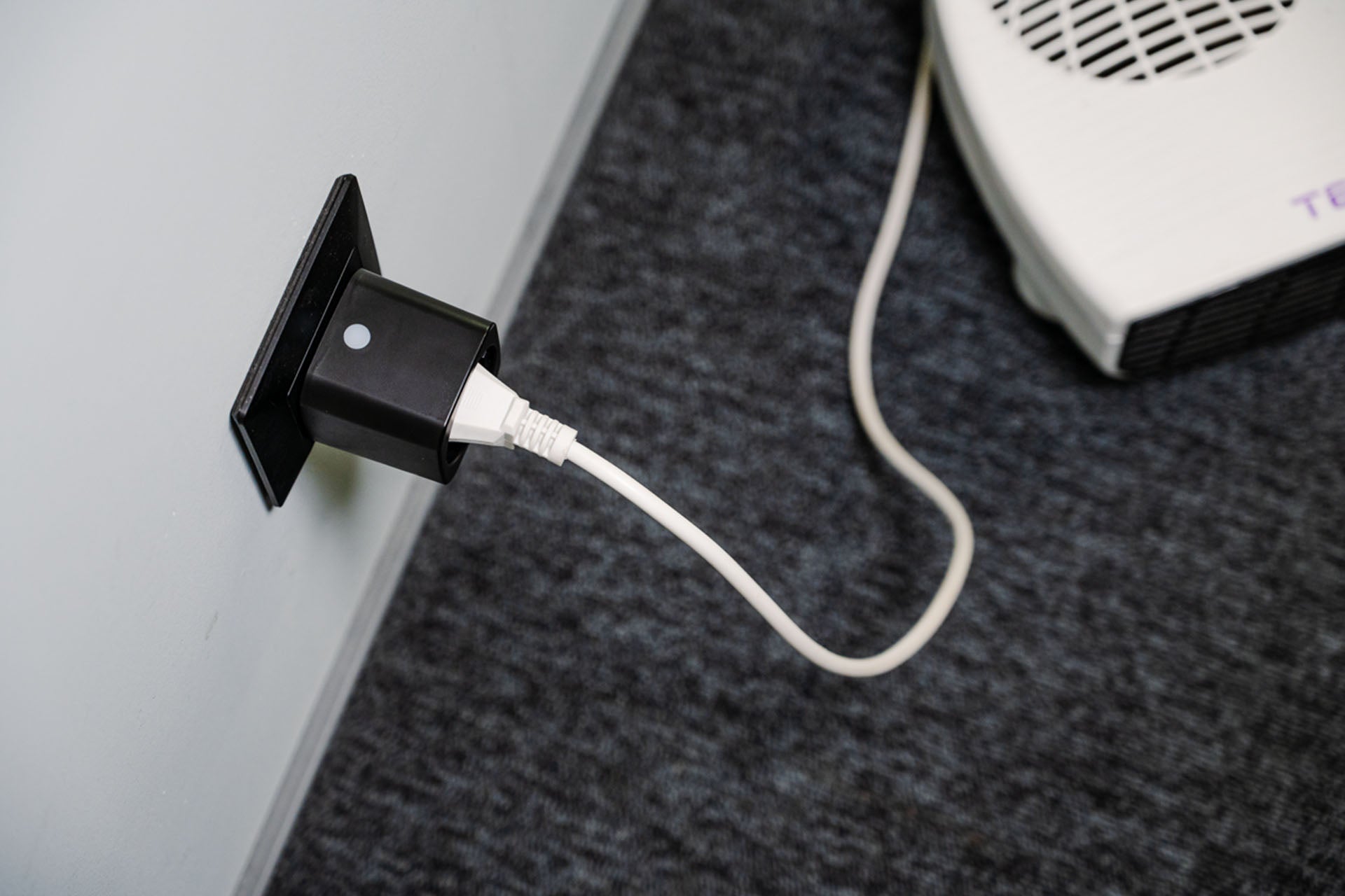 Zásuvka Shelly Plug M Gen3 zapojená do přenosného topného tělesa na koberci