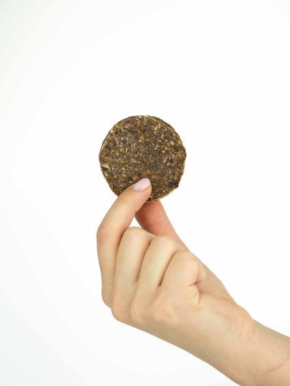 Ruka drží jeden hovädzí hamburger pre psov na bielom pozadí