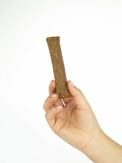 Ruka drží jeden mäsový plátok z králičieho mäsa - Panakei žuvací pamlsok pre psov na bielom pozadí