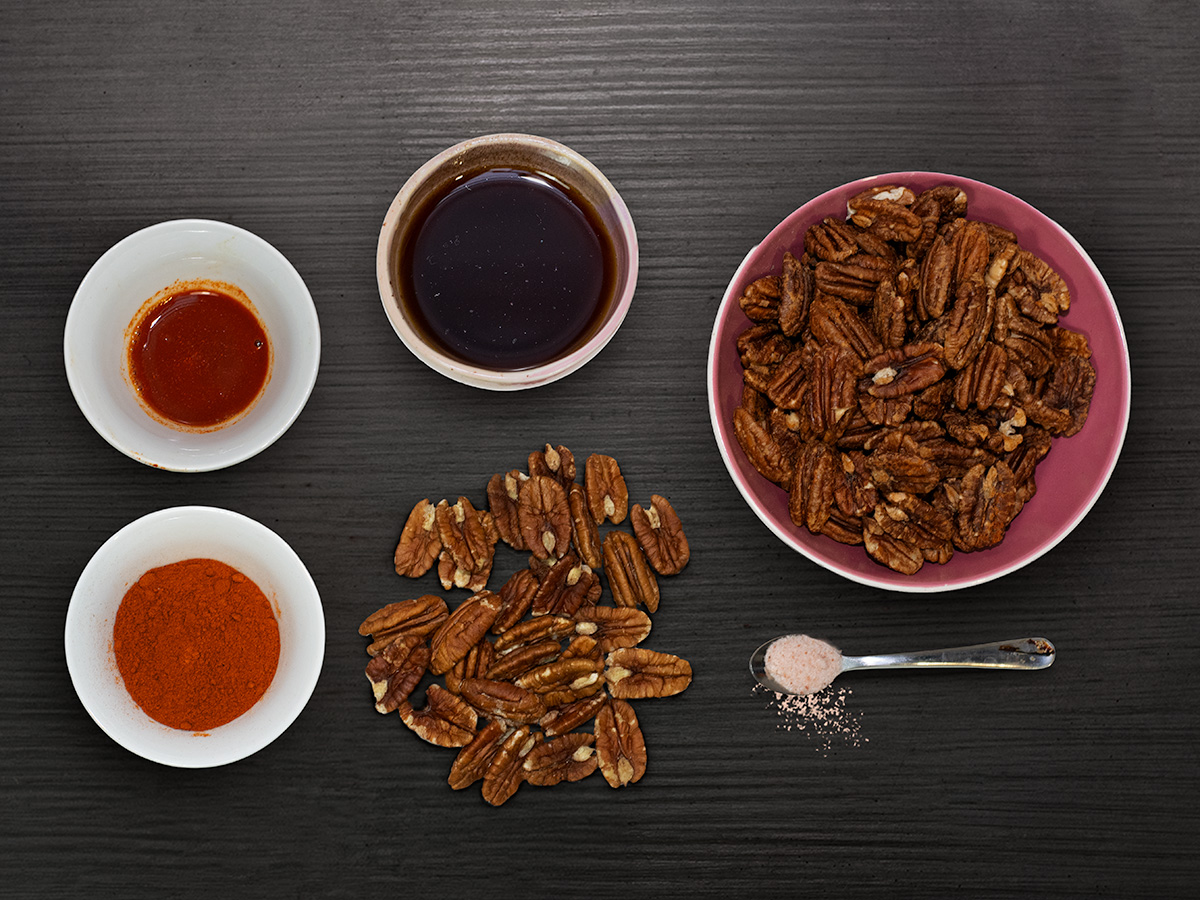 Cayenské pekany a koreniny — flatlay na tmavom dreve