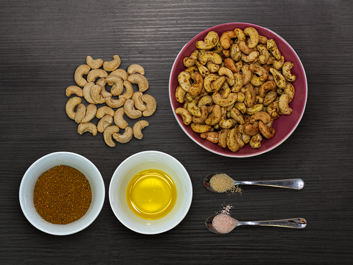 Kešu s kari a koreniny — flatlay na tmavom dreve