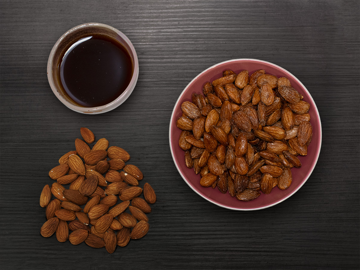 Mandle a javorový sirup — jediné dve suroviny, flatlay na tmavom dreve