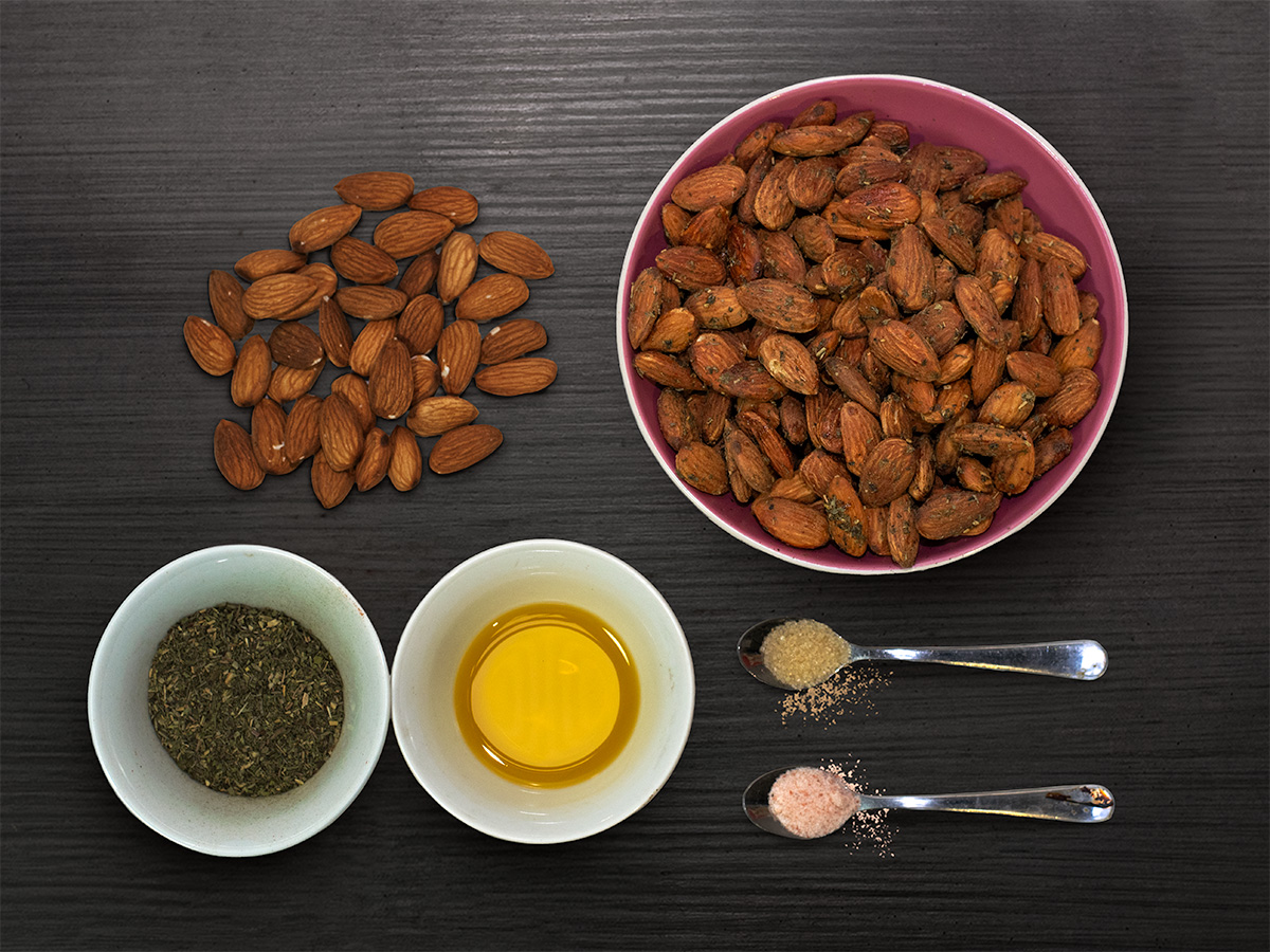Mandle s talianskym korením a bylinky — flatlay na tmavom dreve