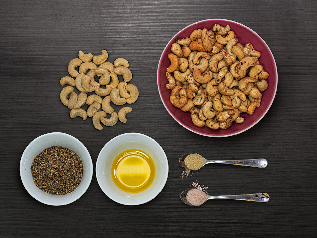 Trojfarebné kešu a koreniny — flatlay na tmavom dreve