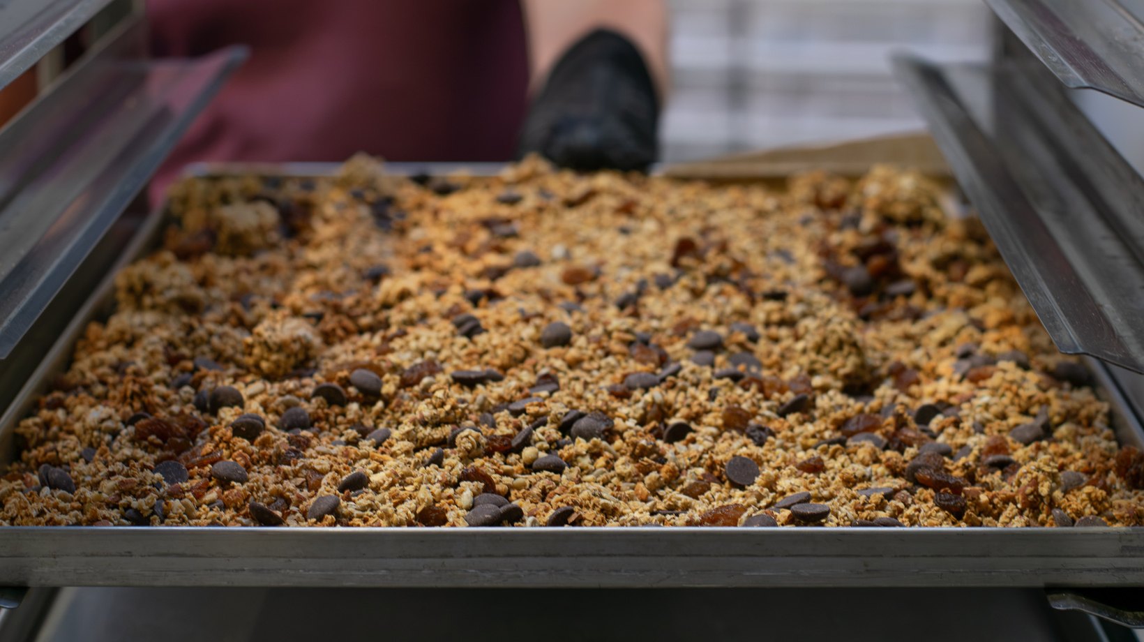 Čokoládová granola rozprestretá v jednej vrstve na plechu, vyberá sa z pece