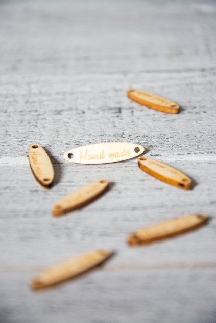 Dřevěná oválná cedulka s provrtanými otvory a nápisem. Rozměr 2,7 x 0,7 x 0,3 cm