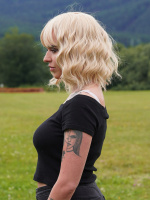  Krátká blond vlnitá paruka s ofinou ze syntetických vlasů.