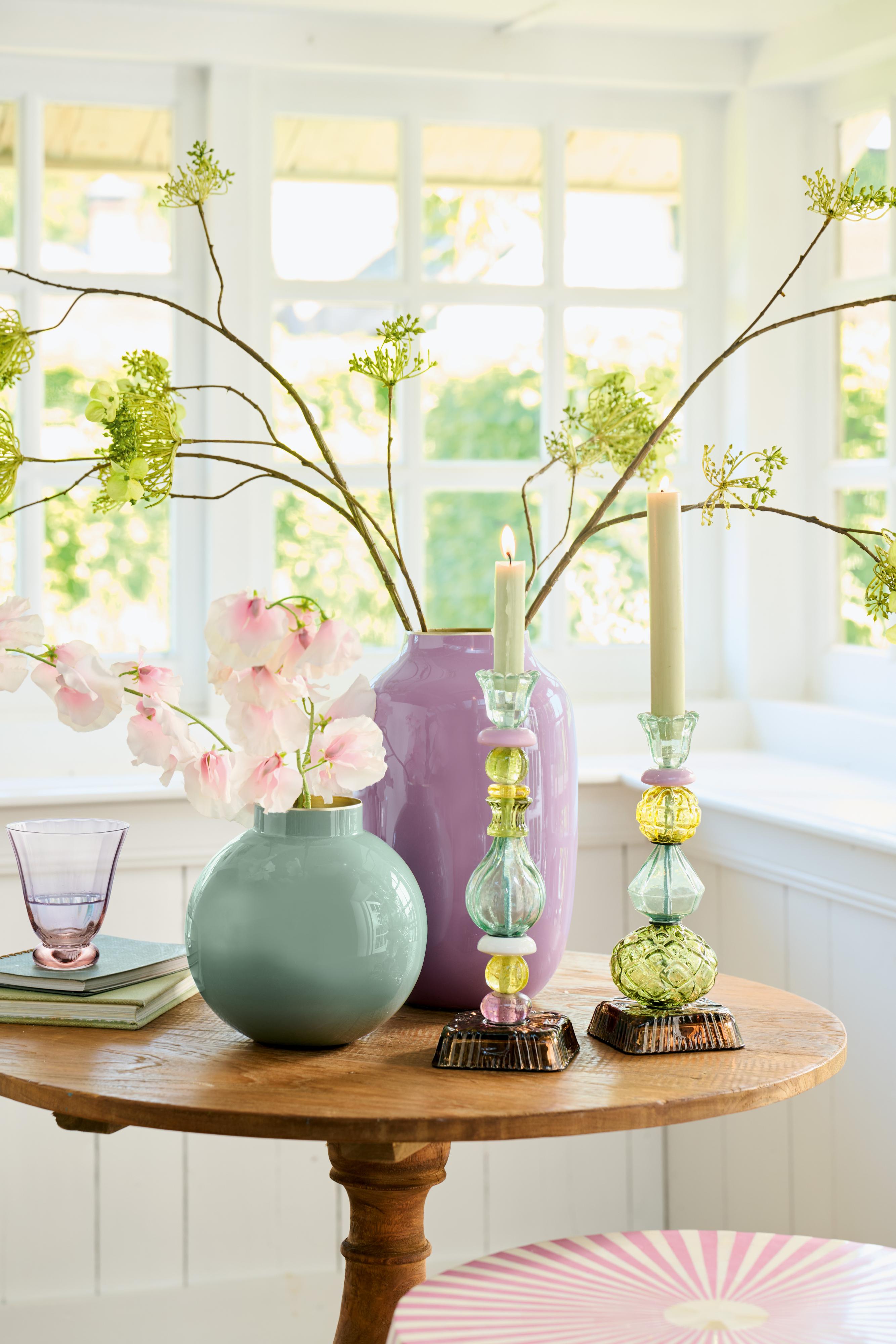 Pip Studio kovová váza malá 17 cm, zelená vedle vysoké oválné vázy Pip Studio v lilá barvě na kulatém stolku s designovým skleněným svícnem Pip Studio Lily&Lotus