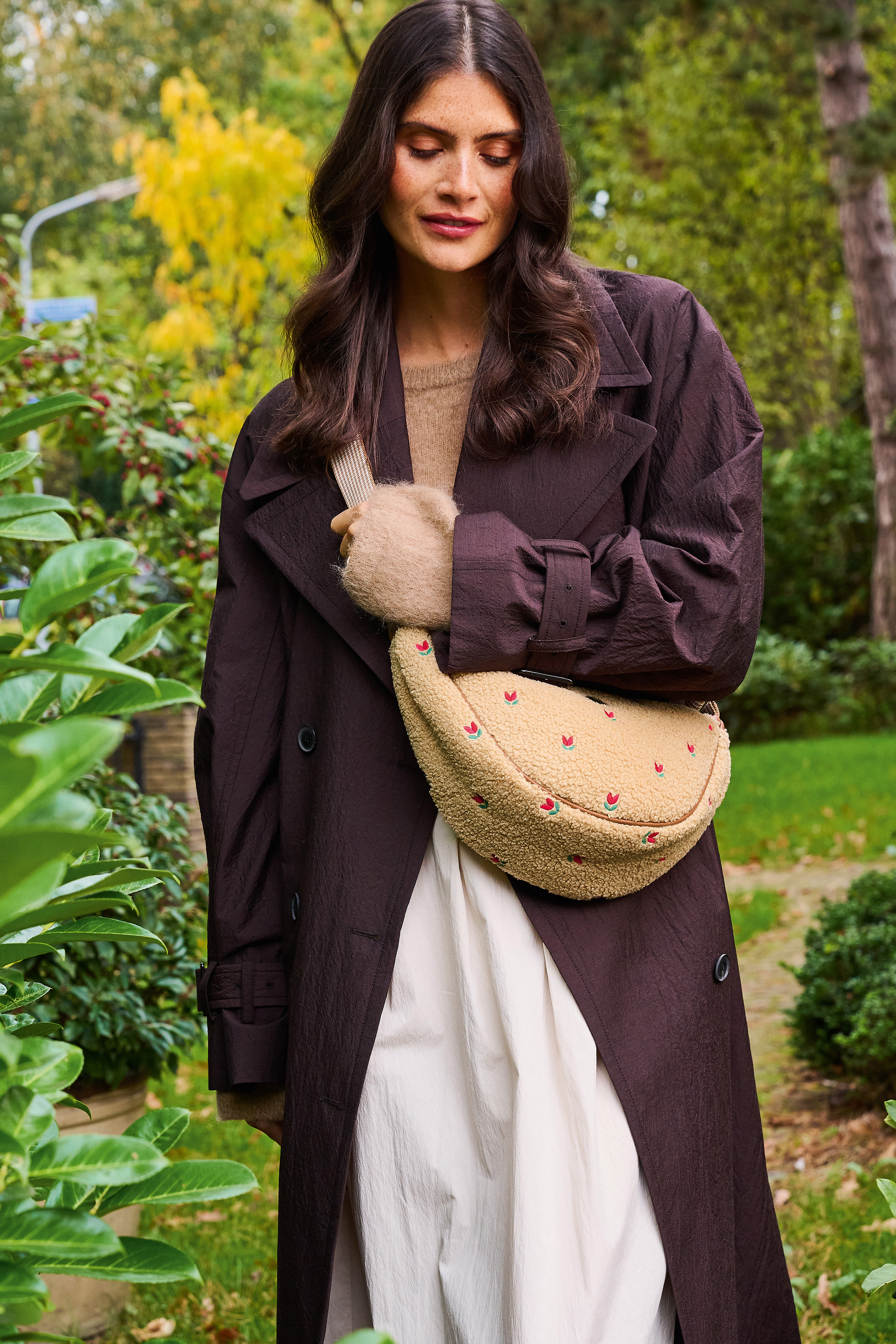 Pip Studio Freya Half Moon Cross Body Teddy Sand kabelka, písková na modelce v tmavě hnědém kabátu v přírodě