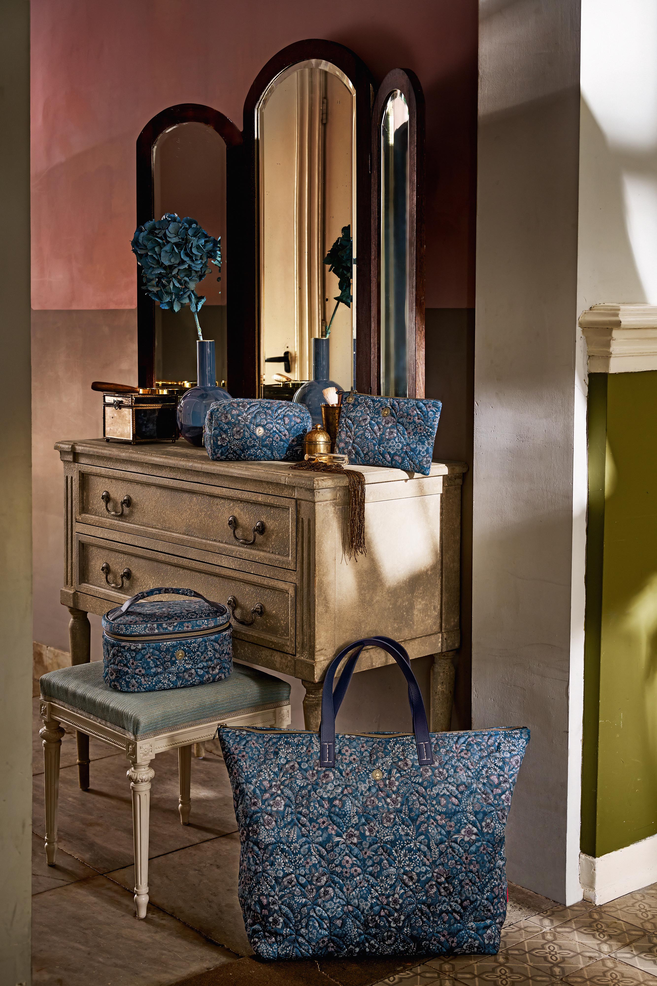 Pip Studio Cleo Quilted Daisy Dreams kosmetický kufr modrý , velká taška, pouch a kosmeticka tštička položene na toaletním stolku a na podlaze , modrá barva s kytičkami kopretin