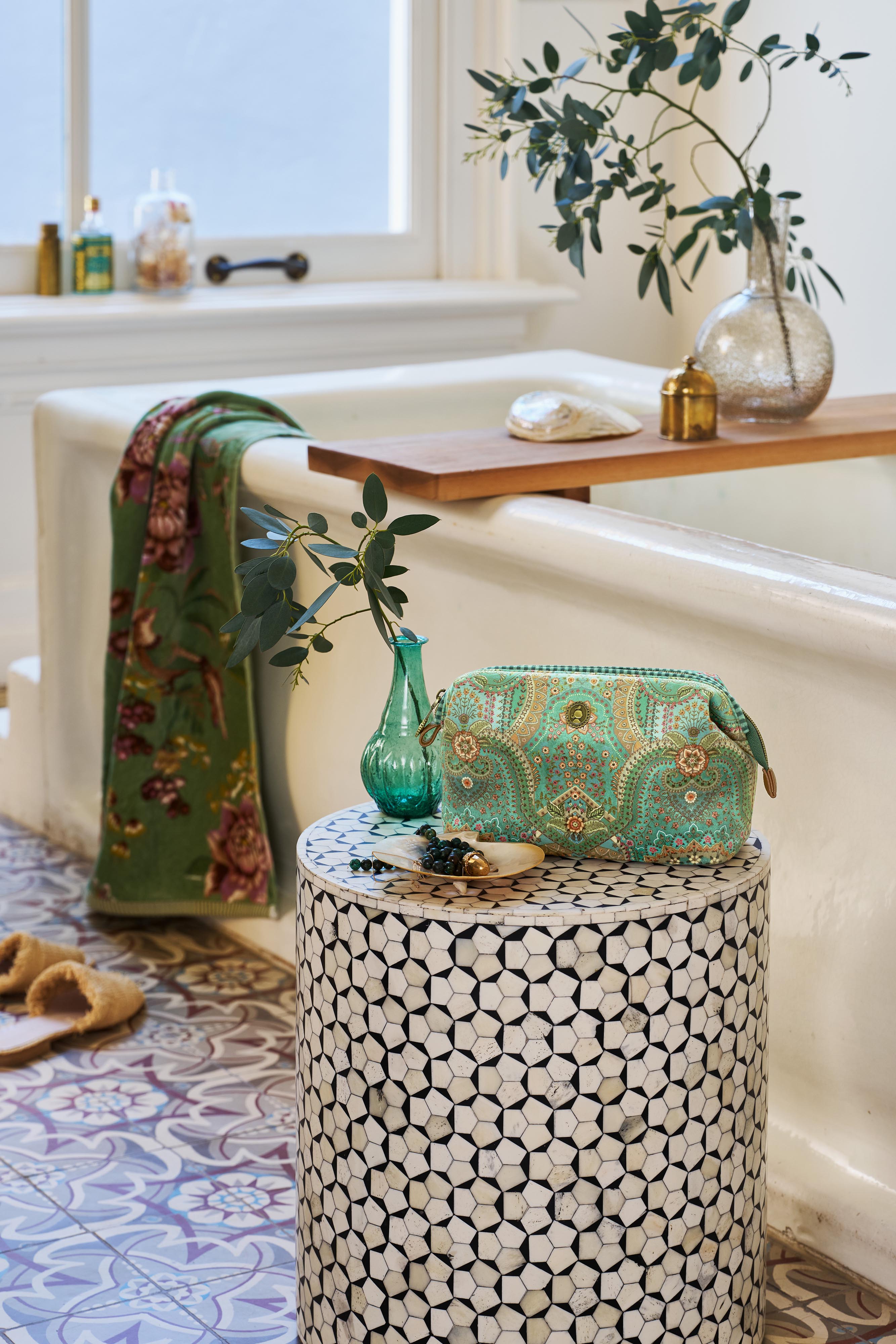 Pip Studio velká kosmetická taška v zelené barvě vzor orientální vzor Jabali položená na stoličce v designové koupelně, na vaně leži osuška Pip Studio Secret Garden zelená s velkými květy
