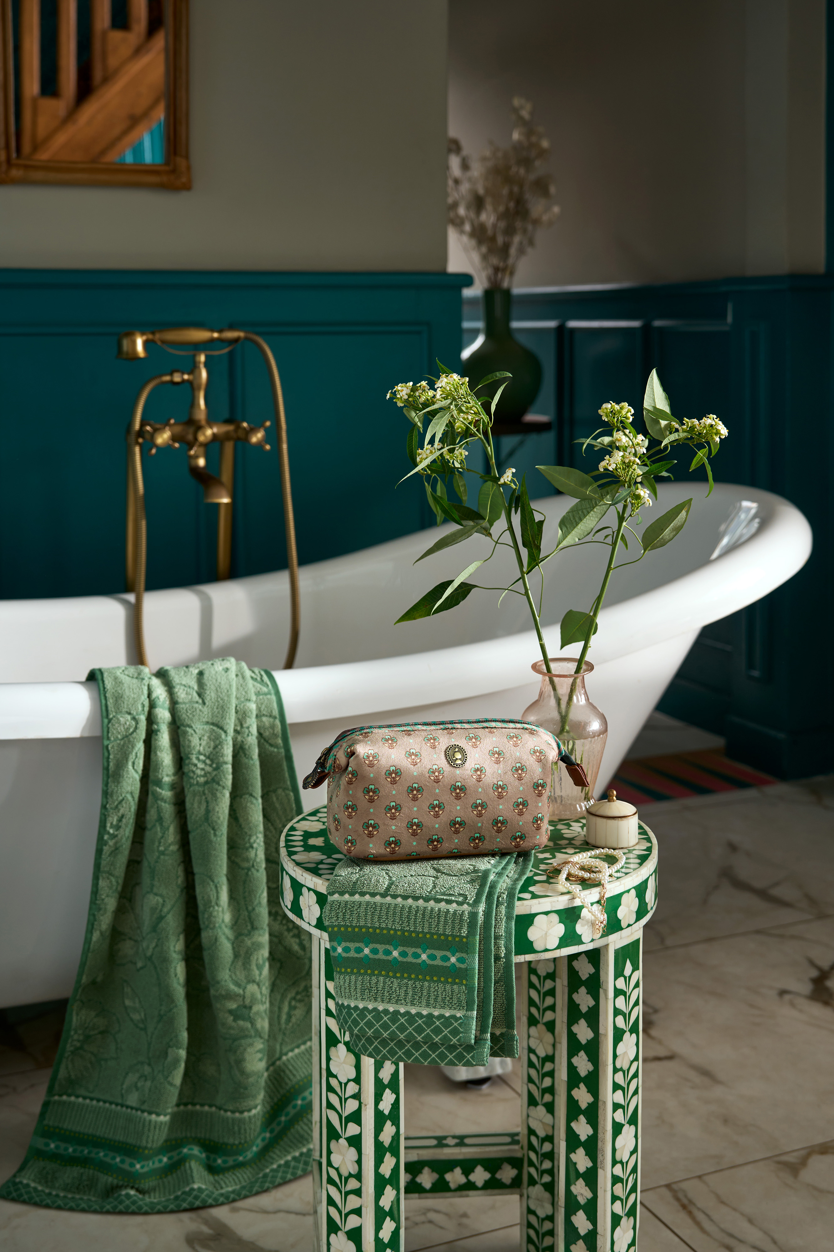 Atmosférické foto Pip Studio kosmetická taška Cooper Jaipur Flower, zelená v designové koupelně postavená na zelenobílé dekorované stoličce vedle volně stojící vany přes kterou je přehozená zelená osuška