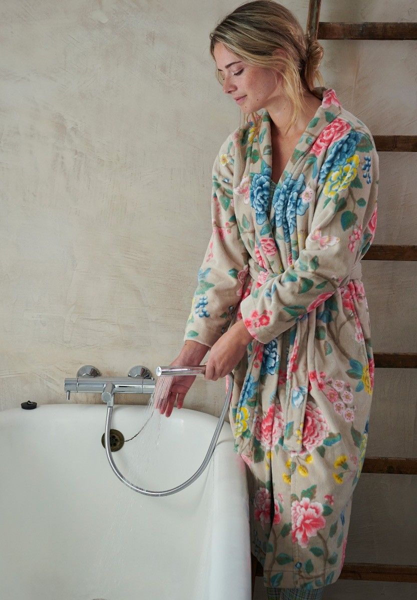 Žena v luxusním velurovém županu Pip Studio s květinovým vzorem si napouští horkou vanu. Domácí wellness rituály a inspirace na elegantní koupelnový textil a oblečení na doma z e-shopu Pipa Ateliér.