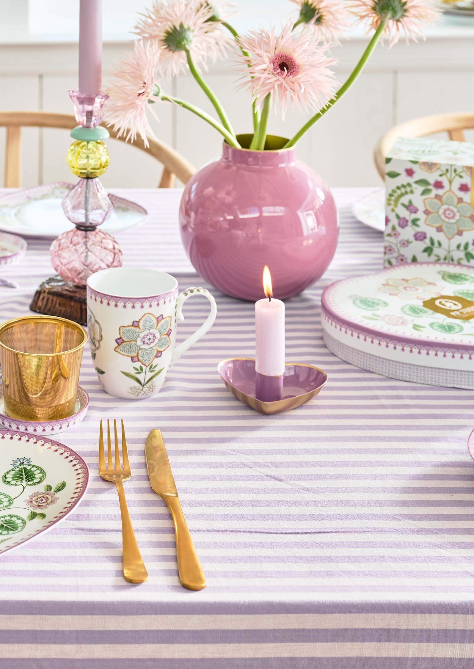 Pip Studio kovová váza malá 17 cm, růžová na prostřeném stole s proužkovaným ubrusem , svíčkou v srdíčkovém svícnu, zlaté příbory a hrnek na čaj Pip Studio Lily&Lotus a taky designový skleněný svícen Pip Studio