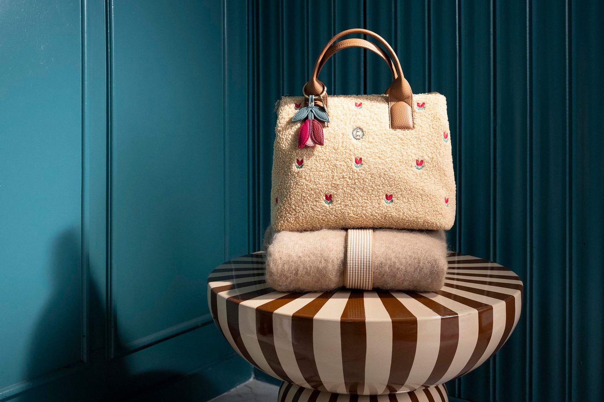 Pip Studio Teddy Fia Sand kabelka, písková položená na huňatém svetru na proužkovaném designovém stolku Pip Studio Living bydlení