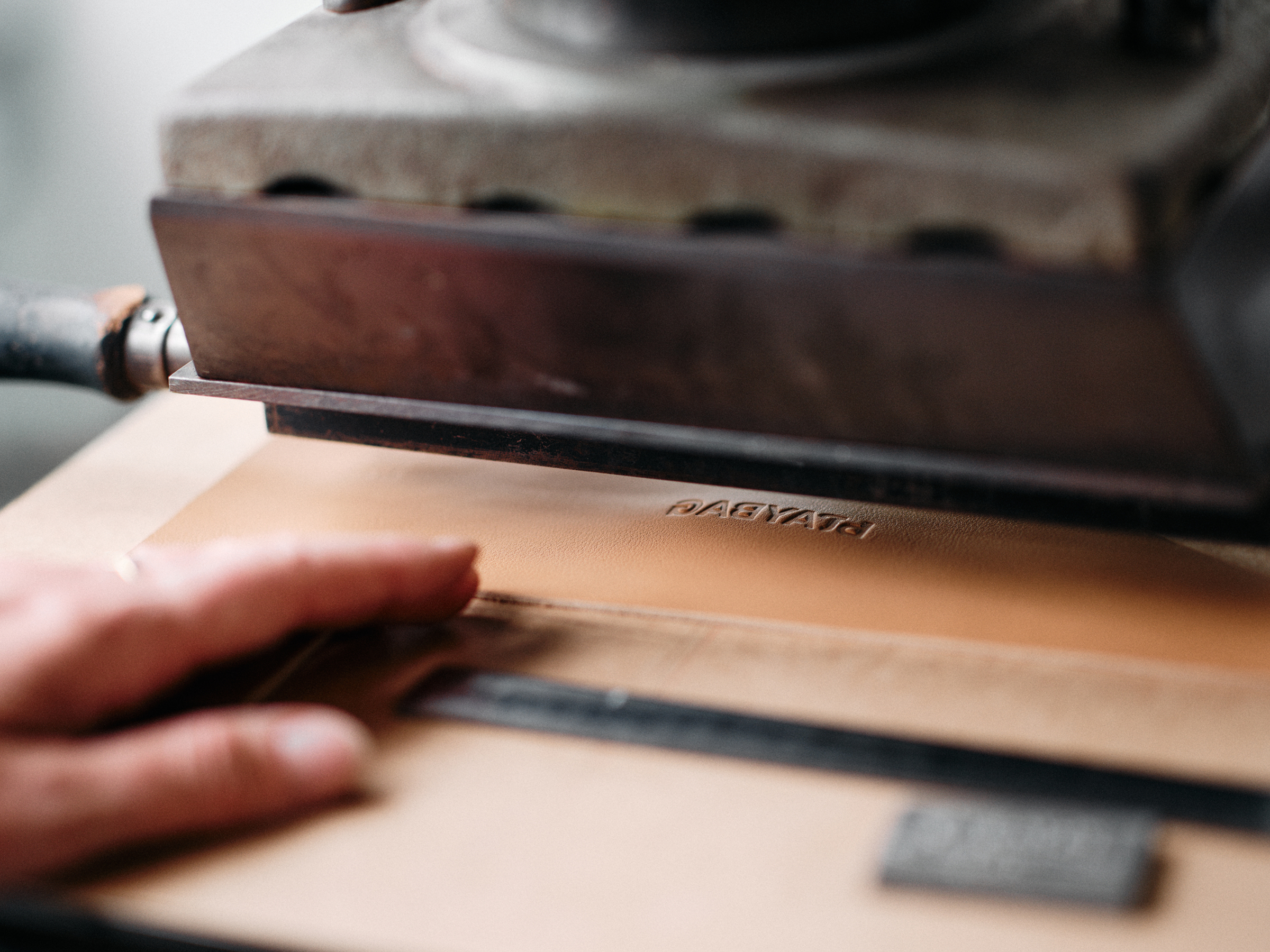 Detailní práce řemeslníka na koženém produktu - ražba