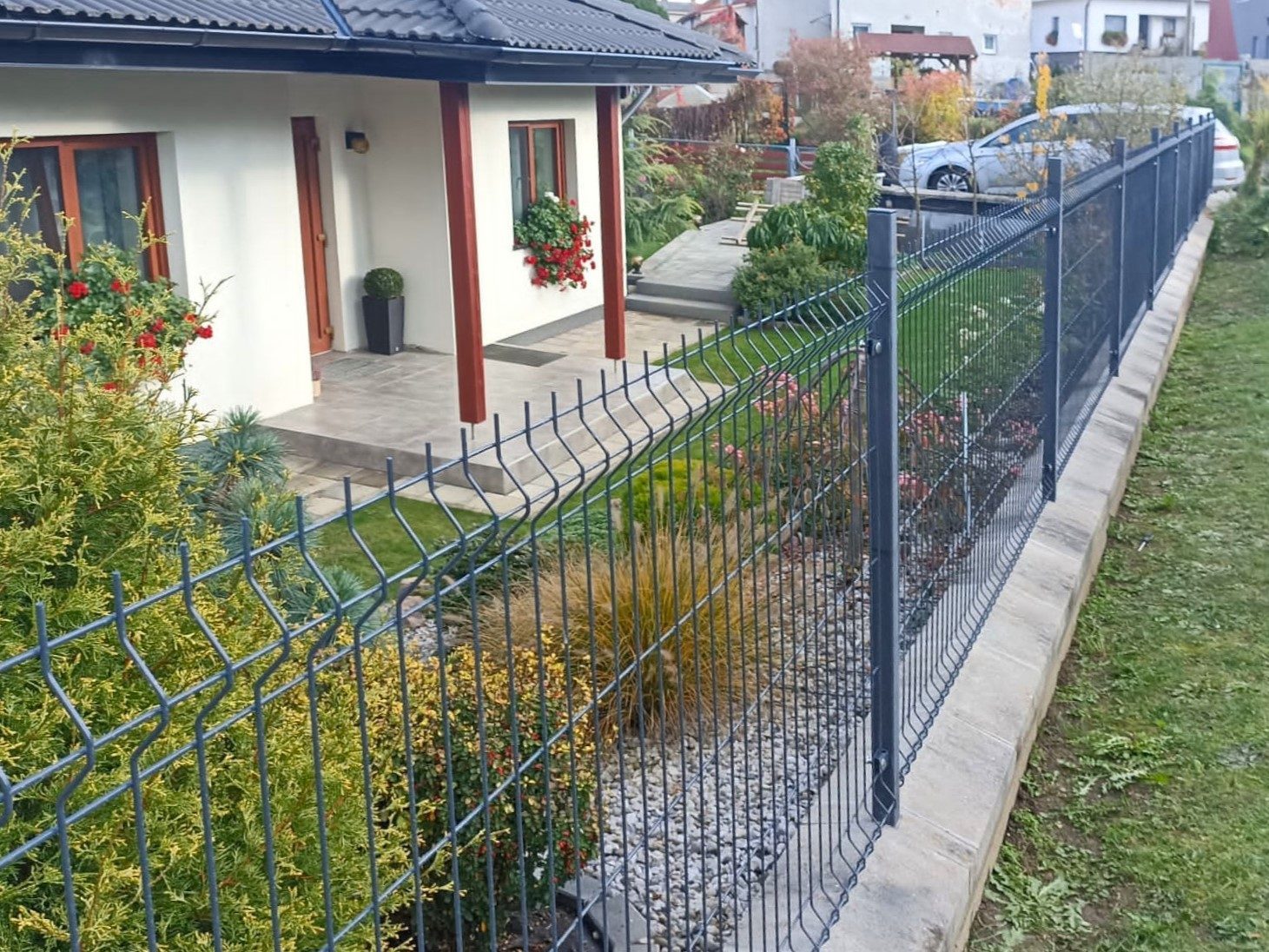 Antracitové 3D plotové panely nad betónovými podhrabovými doskami pred rodinným domom
