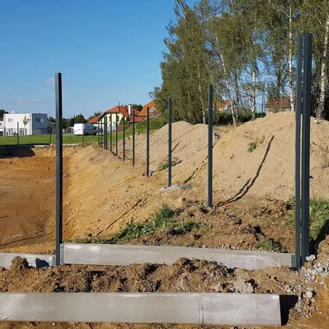 Inštalácia hranatých stĺpikov a podhrabových dosiek – detail rohu pozemku.