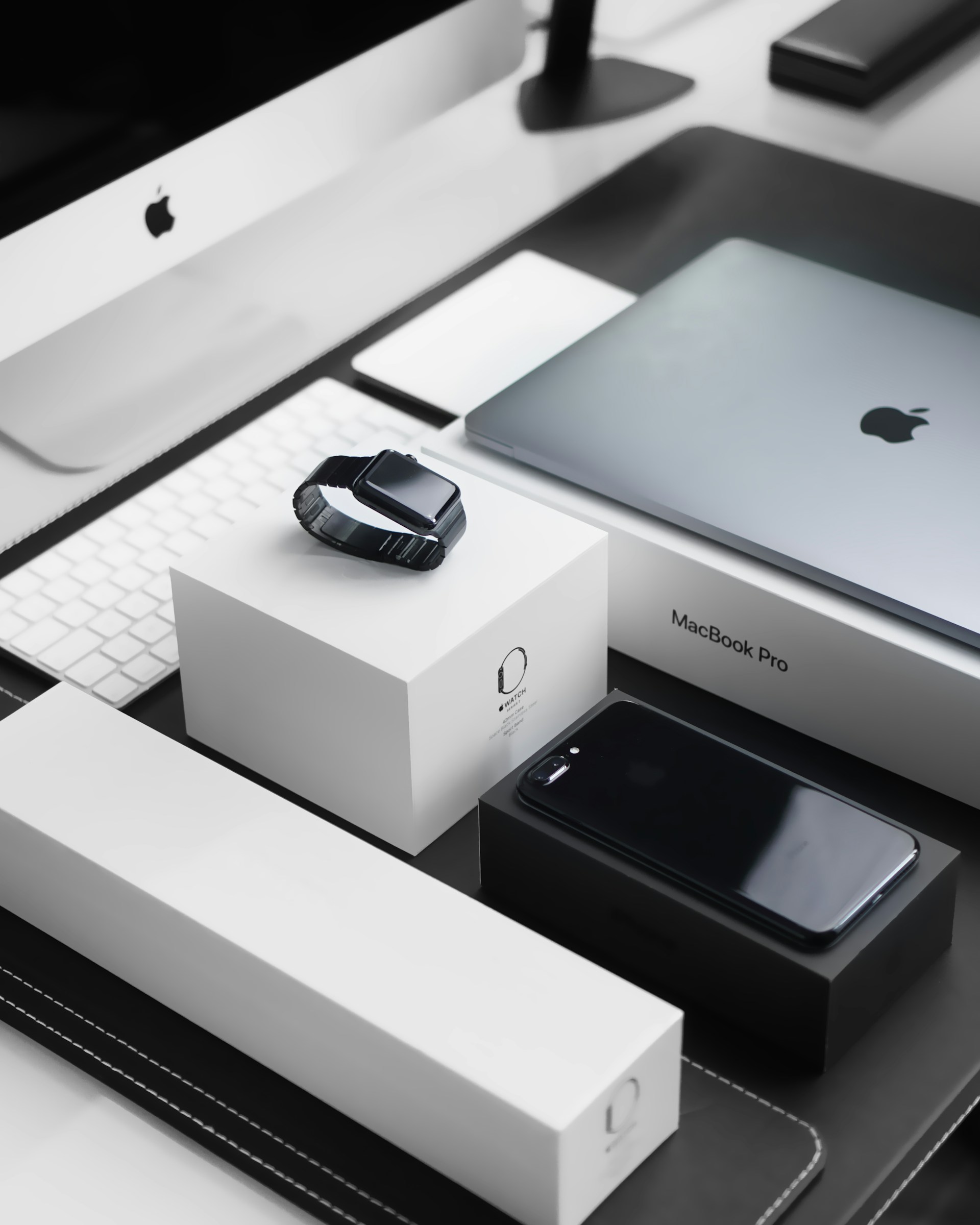 Viacero zariadení Apple a ich balení na pracovnom stole.
