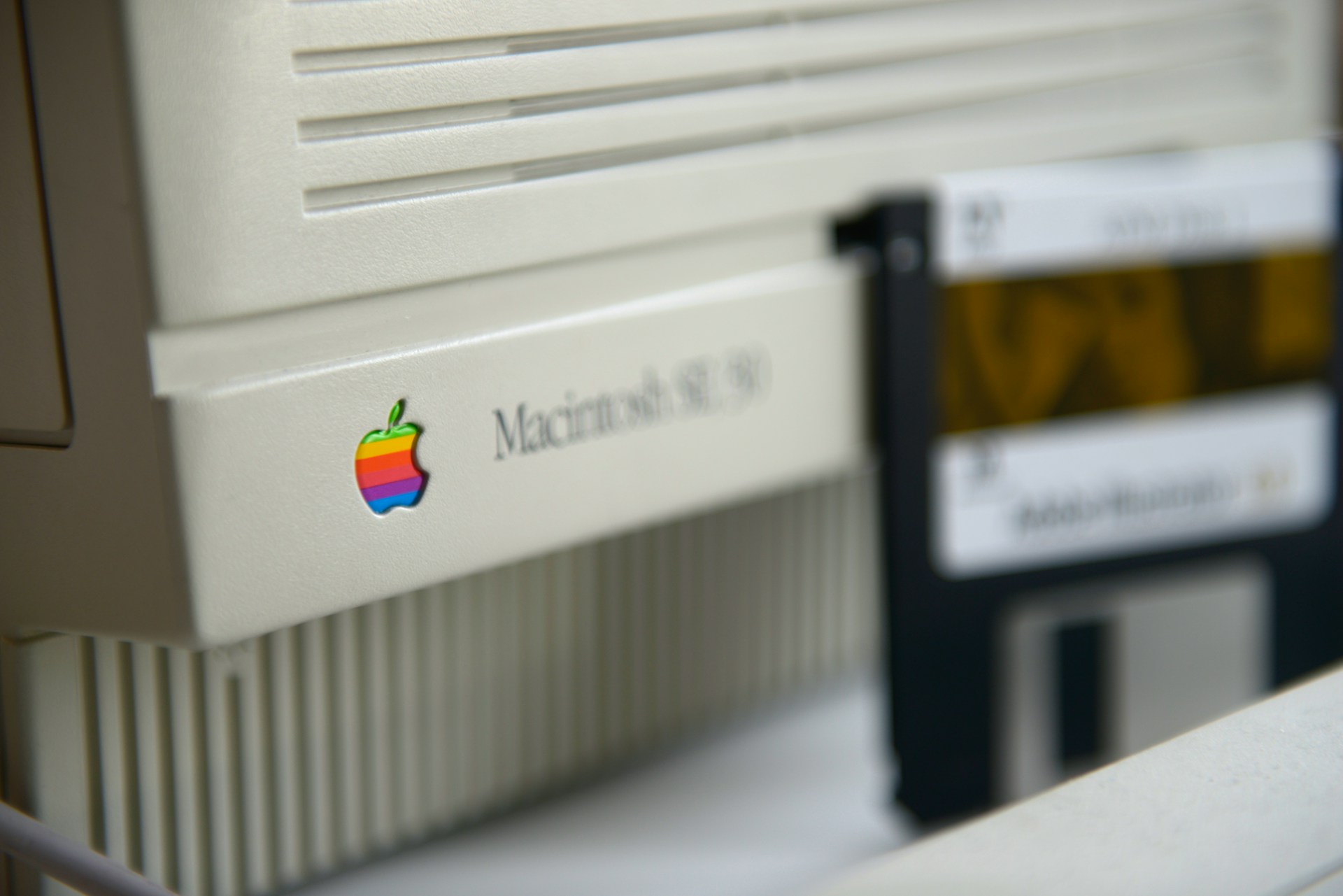 Detail staršieho počítača Macintosh s dúhovým logom Apple.