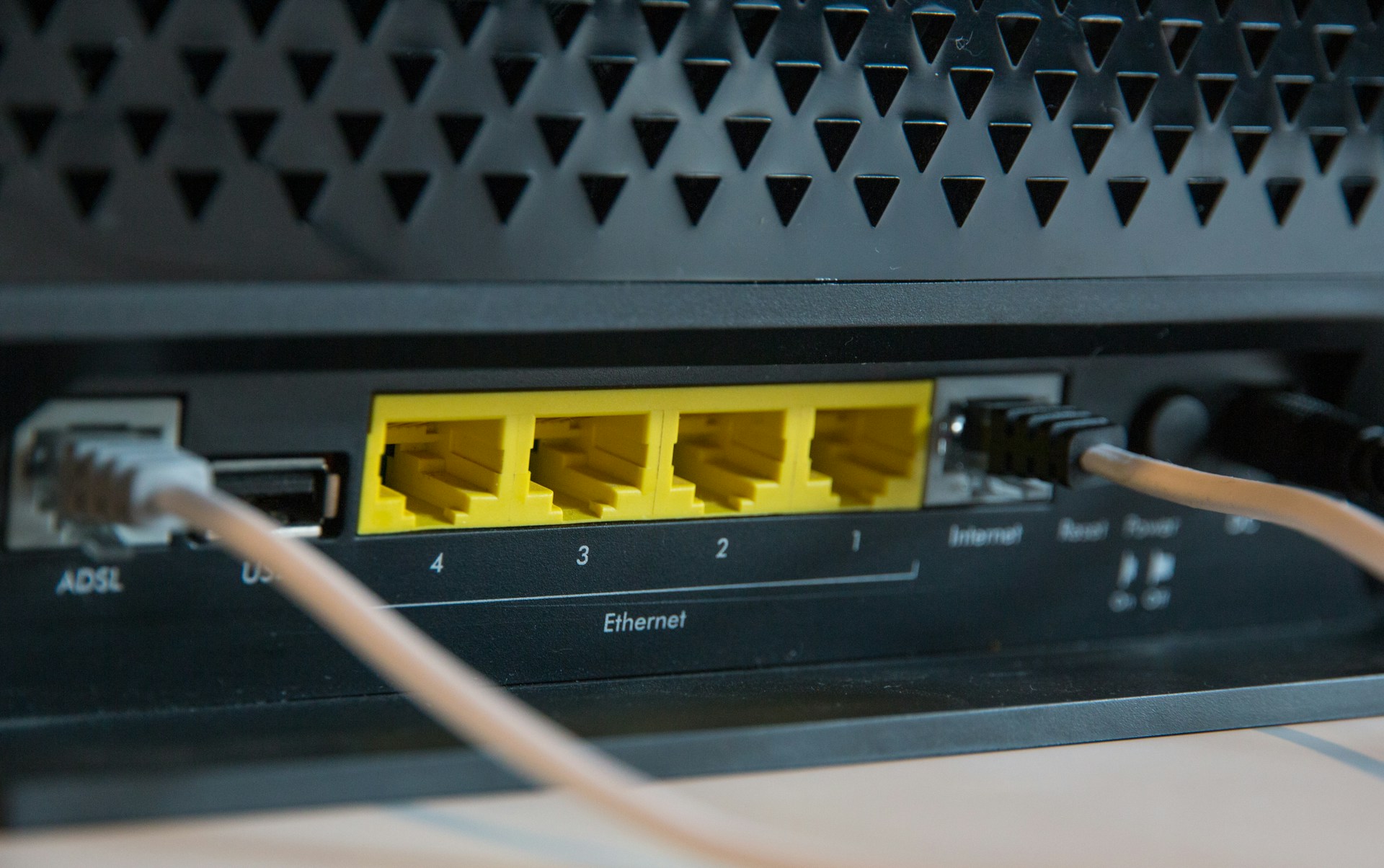 Zadná strana domáceho routera s ethernetovými portmi a pripojenými káblami.