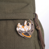 Designový kovový pin s motivem kosmonauta a měsíce připnutý na khaki batohu