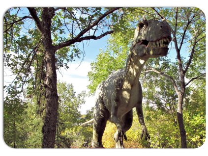 Dětské prostírání s realistickým motivem dinosaura mezi stromy, přirozené prostředí s modrou oblohou, zábavný motiv na stůl.